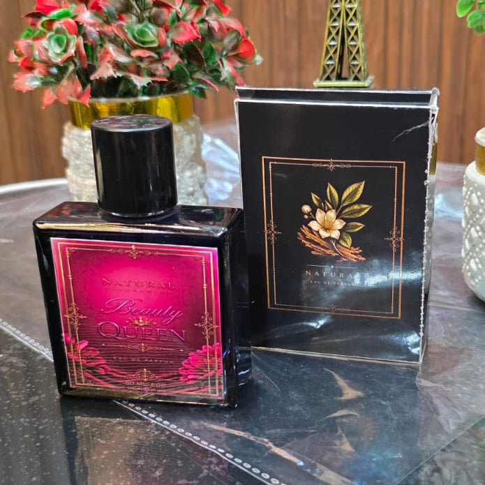 Perfume bottle with pink light, book, and plants on a reflective surface
