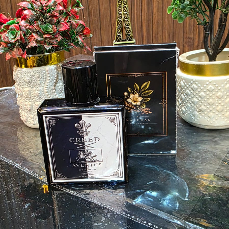 Perfume bottle with packaging on a reflective surface with decorative items in the background